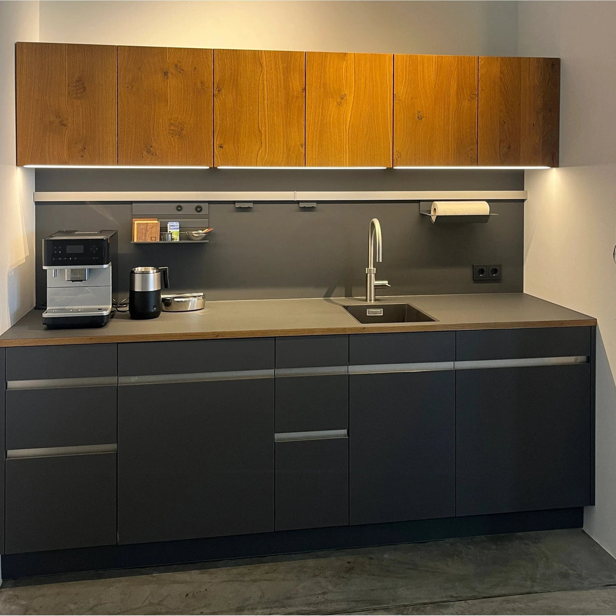 Schwarze kleine Büro Teeküche mit einer Eichenholz-Front in der Ausstellung der Küchen Schreinerei bei  Stuttgart und Ludwigsburg.